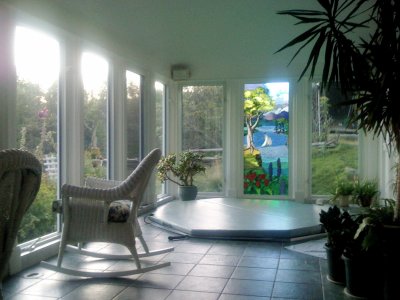 glassed in room with hot tub plants and wicker chairs